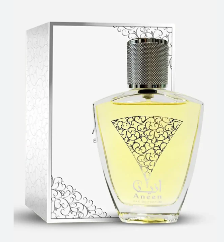 A bottle of Aneen Eau de Parfum with light yellow liquid, standing in front of its white and silver patterned packaging box.