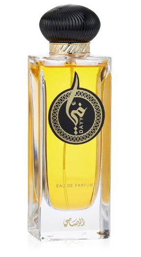 A rectangular clear glass perfume bottle filled with golden-yellow liquid, featuring a black ribbed cap, a gold neck band, and a black circular label with gold Arabic script and the word 'DAY'.