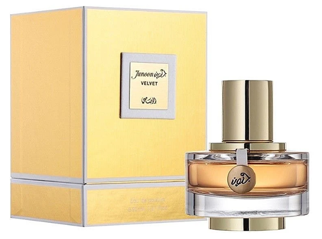 A bottle of Junoon Velvet KBD perfume with a gold cap and amber liquid, shown next to its yellow packaging box with silver trim.