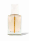 A clear glass perfume bottle with a white cap, filled with pale peach-colored fragrance liquid and featuring a vertical gold label with white text, set against a plain white background.