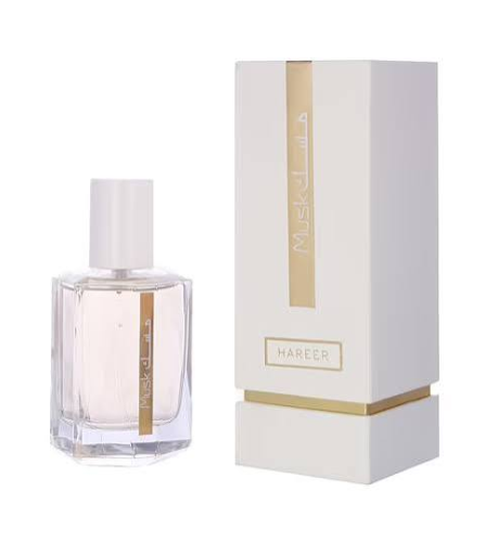 A clear glass perfume bottle with pale pink liquid and a white cap, shown next to its white and gold box. The box features vertical Arabic text and a gold band near the bottom.