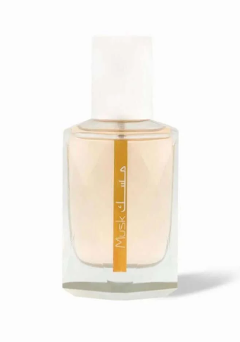 A clear glass perfume bottle with a white cap, filled with pale peach-colored fragrance liquid and featuring a vertical gold label with white text, set against a plain white background.