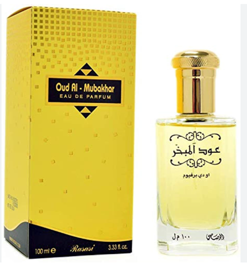 Oud Al - Mubakhhar Eau de Parfum by Rasasi, featuring a yellow patterned box and a clear glass bottle filled with pale yellow liquid, both with gold caps, on a white background.