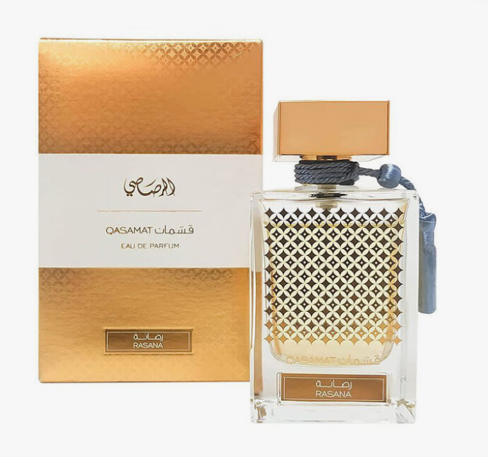 A bottle of Qasamat Rasana Eau de Parfum next to its gold and white packaging box, featuring a geometric patterned glass bottle and a gold cap on a white background.