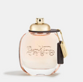 A Coach perfume bottle with a gold cap and a hanging black leather keychain tag featuring the Coach logo, set against a clean white background.