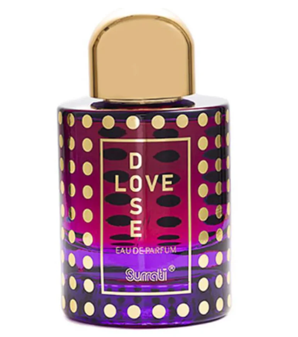 A bottle of Suratti 'Love Dose' Eau de Parfum with a purple body covered in gold polka dots, featuring a gold cap and a gold-bordered label with the text 'LOVE DOSE'.
