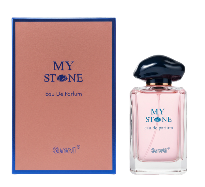 A bottle of Surrati My Stone Eau De Parfum with a dark blue mushroom-shaped cap and pink liquid, shown next to its pink and blue packaging box on a white background.