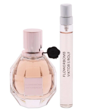 Victor & Rolf Flowerbomb perfume bottle next to a matching Flowerbomb Viktor & Rolf travel spray atomizer, both featuring a pale pink liquid and silver caps on a white background.