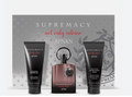 AFNAN Supremacy 'not only intense' fragrance gift set featuring a central dark amber bottle with a silver ring handle, flanked by a black showering shower gel tube and a black soothing after massage balm tube, set against a gray patterned gift box.