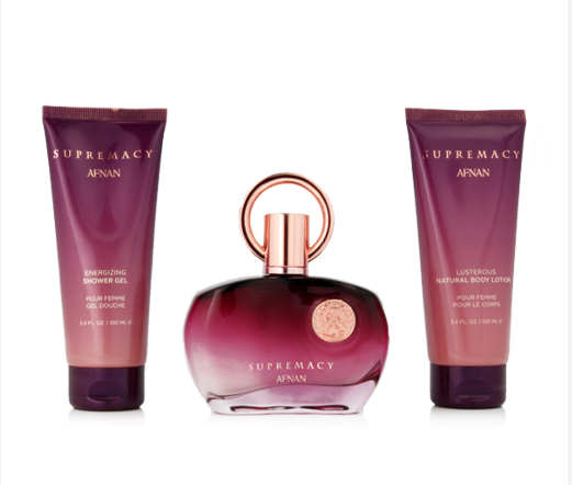 A three-piece Afnan Supremacy body care set on a white background, featuring a central burgundy bottle with a rose gold ring cap, flanked by a shower gel tube and a body lotion tube.