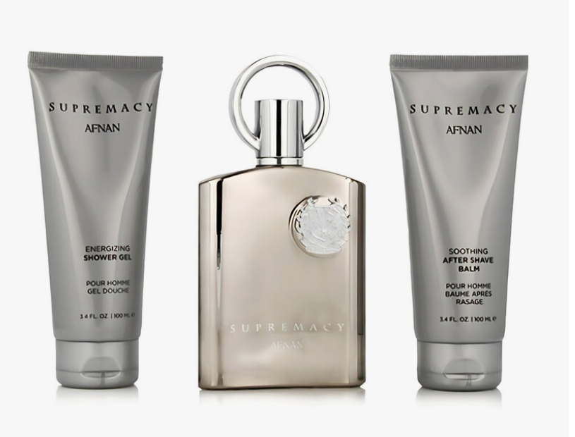 A three-piece men's grooming set by Afnan Supremacy, featuring a metallic champagne-colored bottle in the center flanked by a silver shower gel tube on the left and a silver after shave balm tube on the right, all on a white background.