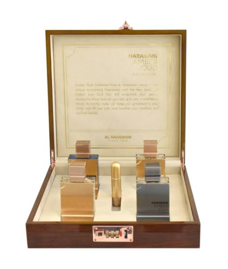 Al Harawain Ambir 300 Collection perfume gift set in an open wooden presentation box with a glass lid, containing four perfume bottles and a cylindrical bottle on a white background.