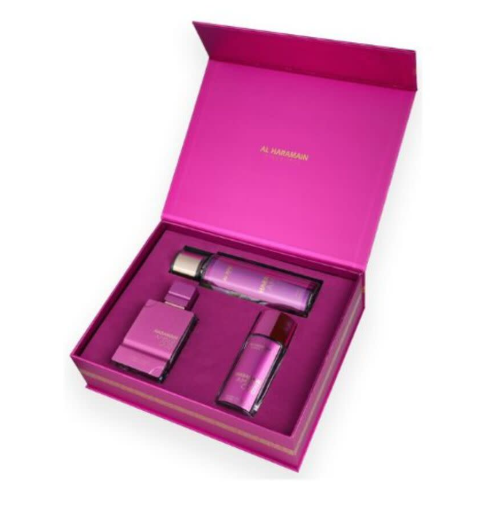 An open bright pink Al Marjan perfume gift set box containing three matching pink fragrance bottles, photographed on a clean white background.