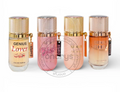 Four perfume bottles from the Genius Rose collection lined up on a white background. The bottles feature metallic gold caps and are filled with liquids in different colors: clear, pink, peach, and an orange-to-clear gradient.