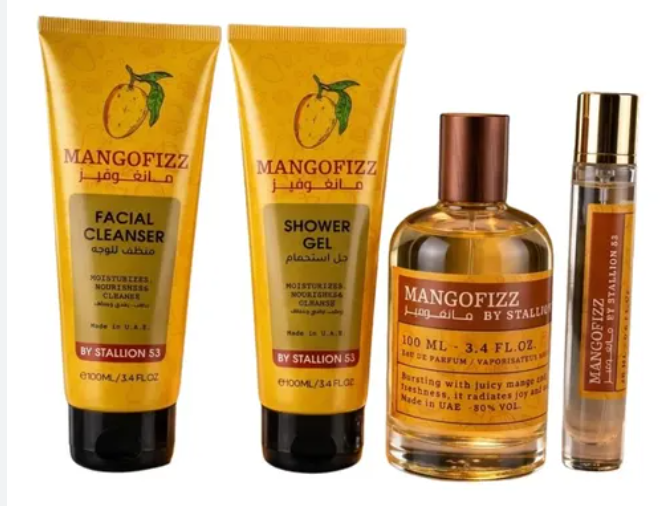 A four-piece skincare and fragrance set from Mangofizz by Stallion SS, including two yellow tubes of facial cleanser and shower gel, a clear bottle of toner with amber liquid and a brown cap, and a small clear spray bottle with a gold cap, all on a white background.