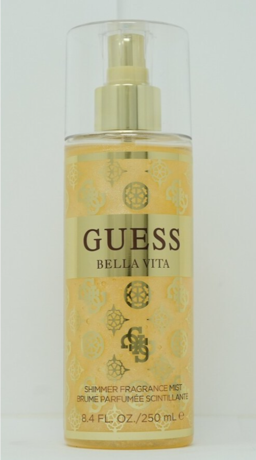 Guess Bella Vita Shimmer Fragrance Mist in a clear spray bottle with a gold pump and a yellow-gold patterned label, shown against a plain light background.