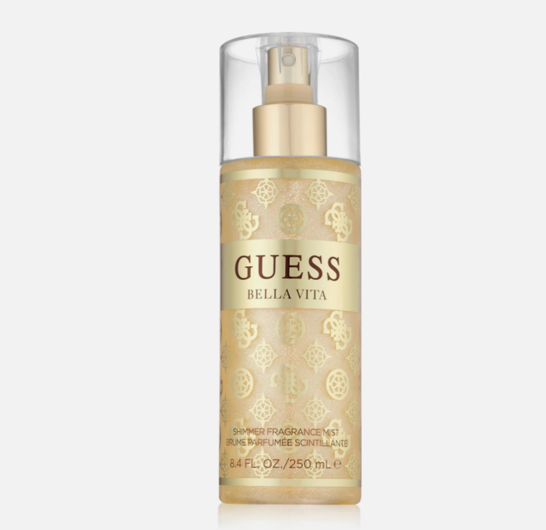 A bottle of GUESS BELLA VITA Shower Fragrance Mist in a champagne gold color with a clear cap and gold pump, set against a light gray background.