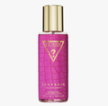 Guess Sexyskin Wild Flower Fragrance Mist in a clear bottle with a textured pink label and a shiny gold cap, shown on a light gray background.