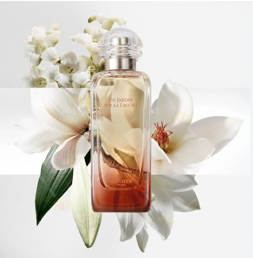 Hermès Élus Jardyn Sur La Lagune perfume bottle with a clear cap, set against a white background with white lilies and green leaves.