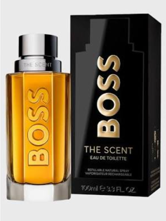 A bottle of BOSS The Scent Eau de Toilette with amber-colored liquid and a silver cap, shown next to its black packaging box with gold lettering.