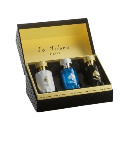 A Jo Milano Paris gift set containing three small bottles of oil or fragrance in white, blue, and black, presented inside an open black and gold box on a white background.