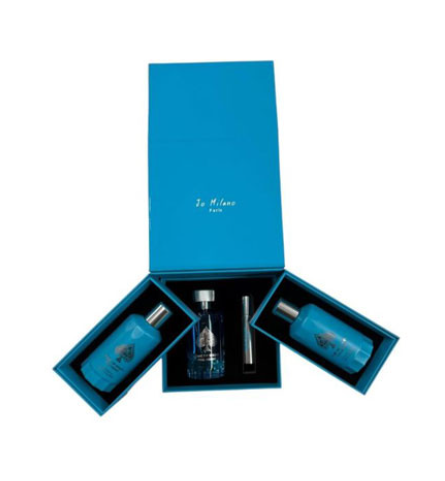 A blue gift set box opened to display two matching blue bottles and a small cylindrical item, with the brand name 'In Milano Paris' printed on the inside lid, on a white background.