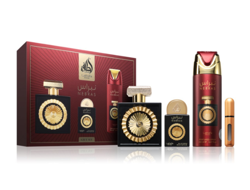 A luxury fragrance gift set featuring a red and gold Nesas perfume box, a rectangular perfume bottle with a gold sunburst cap, a cylindrical body spray bottle, a small round bottle, and a slim travel-sized tube, all arranged on a white reflective surface.