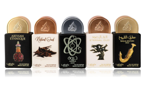 Five Laaloo fragrance bottles lined up on a reflective white surface, each with a different cap color and label design: Artisan Ethnique in gold, Natural Devil in rose gold, Eternal Oud in black, ETERNAL OUD in beige, and Shag Al Baladi Gold in gold.
