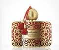 A luxury perfume bottle for Casabella Twilight by Alhambra, featuring an ornate gold and red patterned body, a spherical gold cap, and a red tassel with gold beads.