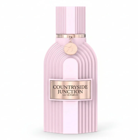 A pale pink ribbed perfume bottle labeled 'Countryside Junction Eau de Parfum' with a metallic gold-toned plaque and hanging tag, centered on a white background.