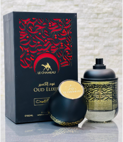 Le Chameau Oud Elixir perfume set featuring a black outer box with red Arabic calligraphy, a round black bottle with a gold lid, and a cylindrical glass bottle with a black cap and gold patterned label, displayed on a reflective surface against a light brick wall.