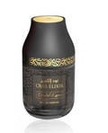 A bottle of Oud Elixir Eau de Parfum with a matte black body, gold Arabic calligraphy pattern, and a gold cap, set against a plain white background with a subtle reflection.