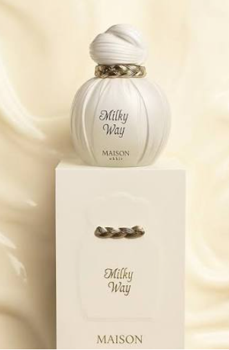 Maison Paris Milky Way perfume bottle and its matching presentation box, set against a soft, draped cream-colored fabric background.