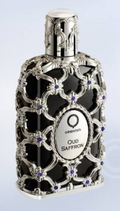 Oud Saffron fragrance bottle by Orientia, featuring a black body encased in ornate silver filigree with small purple gemstone accents, on a light blue gradient background.