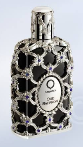 Oud Saffron fragrance bottle by Orientia, featuring a black body encased in ornate silver filigree with small purple gemstone accents, on a light blue gradient background.