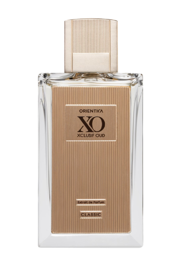 A bottle of Xcluse Oud Orienta Classic Eau de Parfum with a clear glass body, a beige textured label, and a matching beige ribbed cap, set against a plain white background.